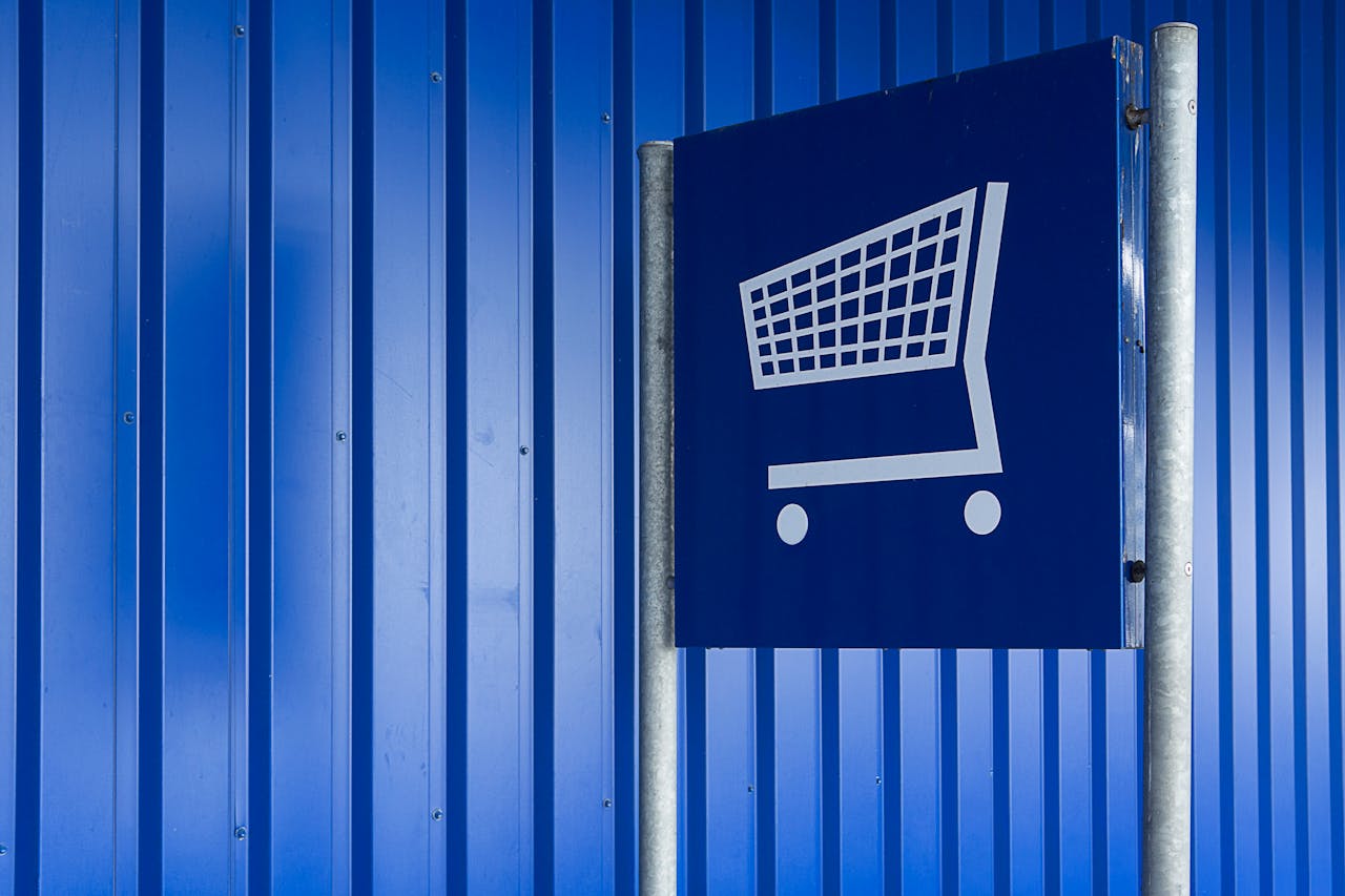 Blue metal wall with a shopping cart sign symbolizing retail or supermarket area.